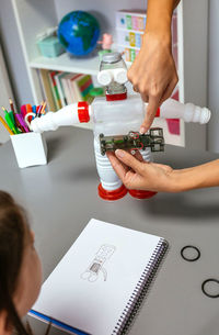 Teacher explaining how to connect electric circuit on recycled toy robot