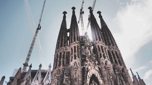 Low angle view of under construction sagrada familia against cloudy sky