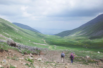 Man standing on mountain against cloudy sky