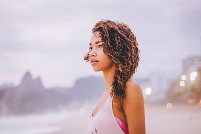 Young woman standing at beach against sky