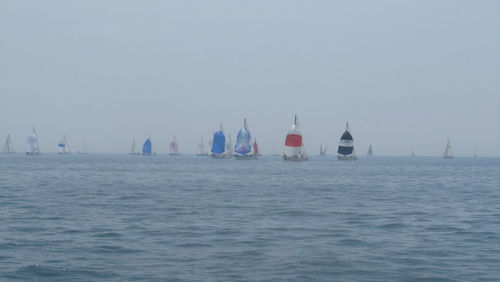 Sailboats sailing in sea against clear sky