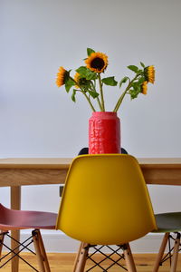 Close-up of yellow flower in vase on table against wall