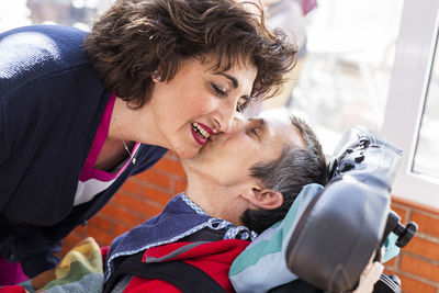 Disabled man kissing female nurse at nursing home