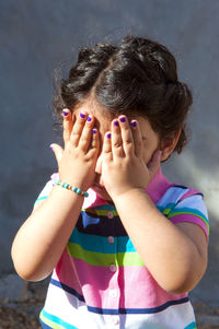 Cute girl covering face while standing outdoors