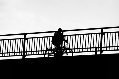Silhouette woman walking on footbridge against clear sky