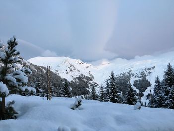 Scenic view of snow covered mountains against cloudy sky