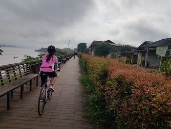 Rear view of woman riding bicycle against sky