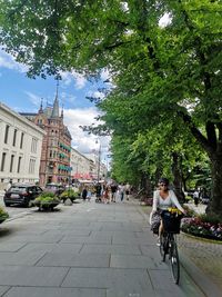 People riding bicycle on street against buildings