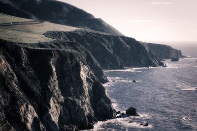 Scenic view of sea by mountains against sky