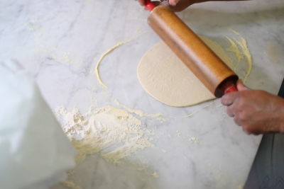 Cropped hands using rolling pin at table in kitchen