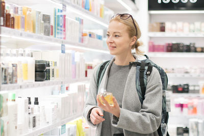 Smiling young woman holding camera at store