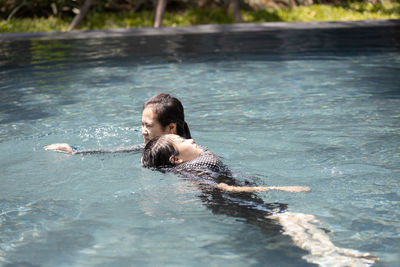 Rear view of shirtless boy swimming in pool