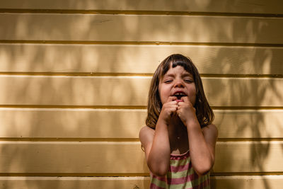 Portrait of funny little child on a sunny day against yellow wall