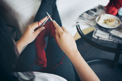 Midsection of woman knitting wool at home