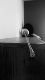 Fencing mask and sword on table by wall