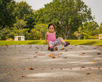 Child riding skateboard in the park. little girl learning to ride skate board. active outdoor sport.