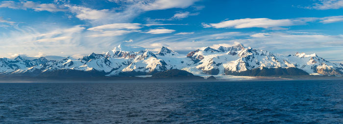 Scenic view of sea and snowcapped mountains against sky