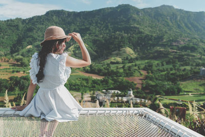 Rear view of woman sitting against mountains