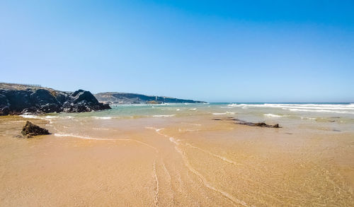 Scenic view of beach against clear blue sky