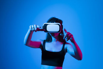 Low angle view of woman photographing against blue background