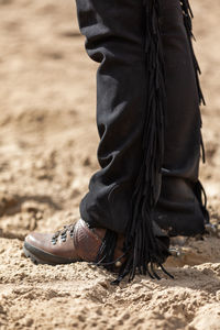 Low section of man standing on sand