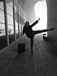 Full length of cheerful woman with suitcase