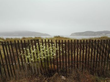 Wooden fence on field against sky