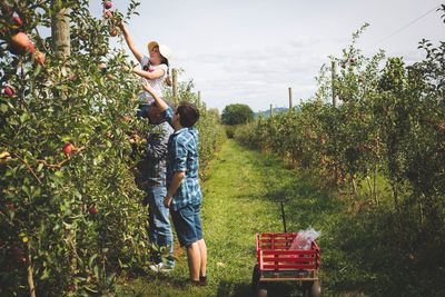 Full length of father with daughter standing on field against trees