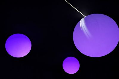 Low angle view of illuminated lighting equipment against black background