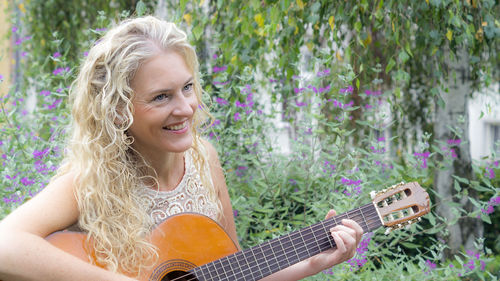 Portrait of a smiling young woman playing guitar