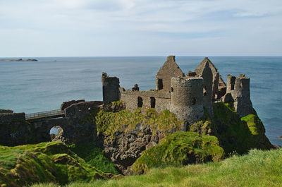 Old building by sea against sky