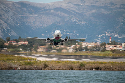 Airplane flying over sea and mountains in city