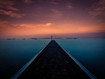 Pier over sea against sky during sunset