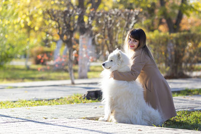 Portrait of smiling woman with dog crouching in park