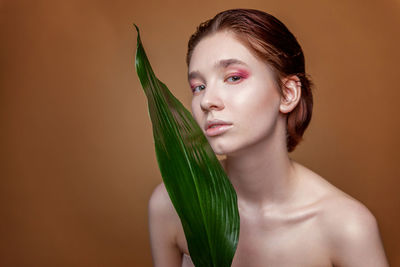 Close-up of young woman against green background