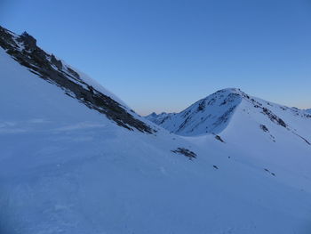 Scenic view of snowcapped mountains against clear blue sky