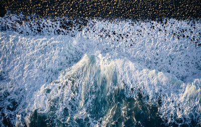 Aerial view of sea waves splashing on rocks