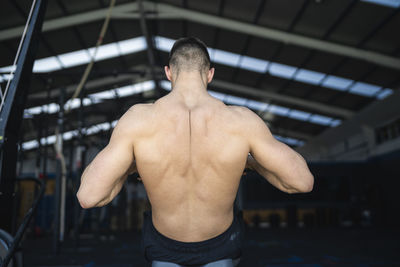 Shirtless male athlete exercising on rowing machine in gym