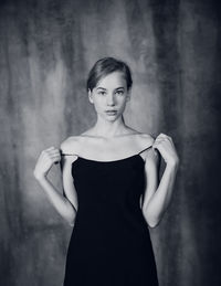 Portrait of young woman standing against wall