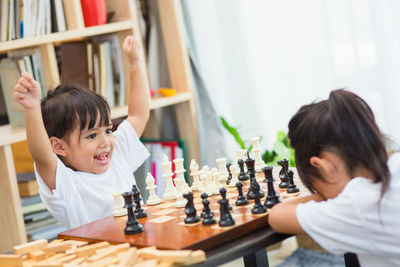 Cute sisters playing chess at home