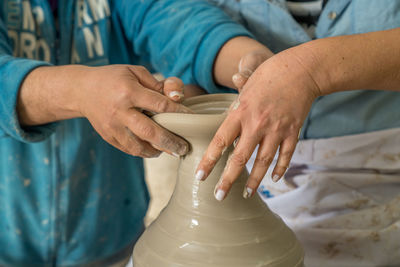 Midsection of people making clay pot