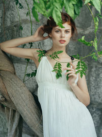 Portrait of young woman against plants