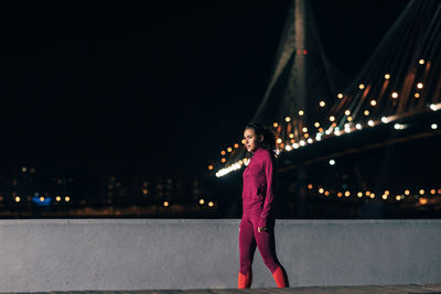 Woman standing on bridge at night