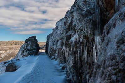 Snow covered cliff by sea against sky