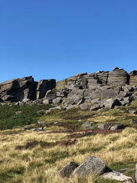 Rocks on land against clear blue sky