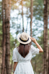 Rear view of woman standing against trees in forest