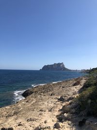 Scenic view of beach against clear blue sky