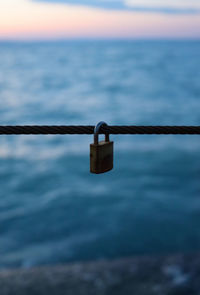 Close-up of padlocks on sea against sky