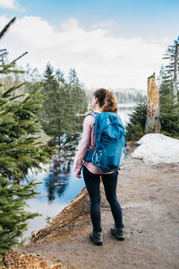 A young girl with a sports backpack on her back walks through the forest, goes hiking.