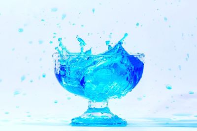 Close-up of water splashing on glass against white background